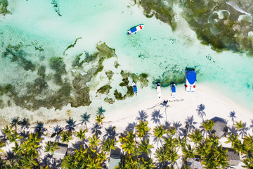 Aerial view from drone on tropical island with palm trees and speed boat shipping in caribbean sea