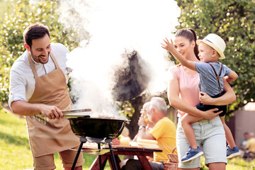 Happy  family barbecuing meat on the grill