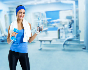 Woman in fitness wear with water, at gym