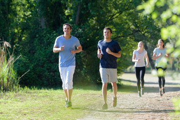 people running on forest trail in spring green trees