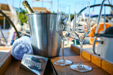 Romantic luxury evening on cruise yacht with champagne setting. Empty glasses and bottle with champagne and tropical sunset with sea background