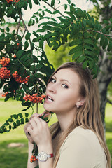 beautiful girl with flowing hair stands near a branch with rowan