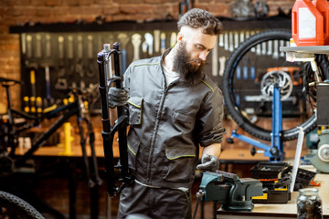 Handsome repairman holding bicycle fork while working in the beautiful bicycle workshop
