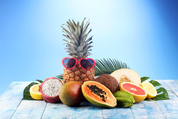 Fresh tropical Fruits on the beach with a palm leave. Assorted tropical fruits, orange,Ananas or pineapple and mango