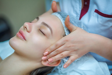 people, beauty, lifestyle and relaxation concept - beautiful young woman lying with closed eyes and having face and head massage at spa