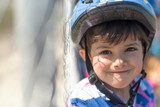 Biker kid near to fences smiling an dlooking at camera