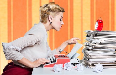 Attractive young woman working on vintage typewriter on  background