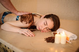 lateral view of a beautiful woman in spa salon having spa therapy with coffee done by a masseur