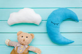 Baby care concept with moon pillow, clouds, teddy bear and toy for sleep of newborn on mint green background top view