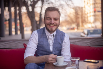 one young smiling man sitting in a coffee shop.