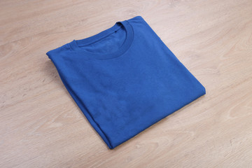Folded blue t-shirt mockup on wooden background