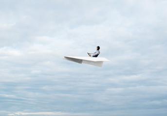Businessman in aviator hat sitting in paper plane