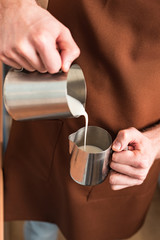 Cropped view of barista pouring milk in steel jug