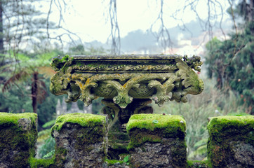 Architecture outdoor details and elements of Quinta da Regaleira. Close up view of the old stone vase with green moss.