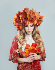 Nice autumn woman in fall leaves crown on gray background
