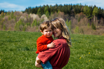 Mother and son on countryside lawn with mountains and forest