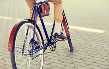 people, style and lifestyle - close up of hipster man riding fixed gear bike on city street
