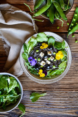 Black bean pasta salad with leafy greens, olives, green peas, sheep cheese and edible flowers