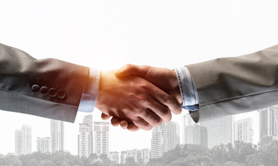 Business handshake as idea for unity and cooperation or greeting. Mixed media