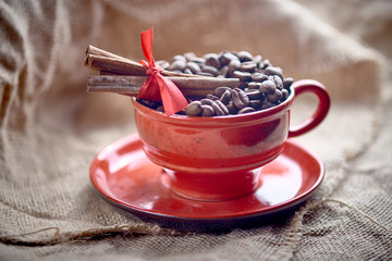 red cup with coffee beans and cinnamon sticks