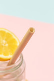 Bamboo straw in a glass of lemon water on the pink background, Reusable bamboo straws as an alternative for single-use plastic straws, healthy and sustainable lifestyle concept