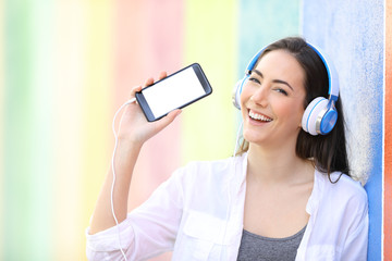 Happy girl listening to music showing phone screen