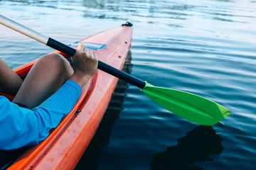 kayaker paddles across a serene lake, focus on the foreground