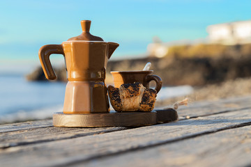 Breakfast on the beach for two. Coffee maker with cups and French croissants. Romantic date background.