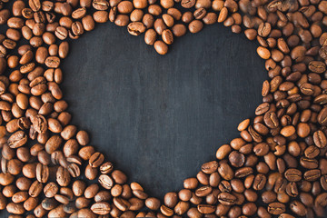  Coffee beans in the form of a heart on a black wooden background. Coffee heart