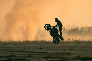 the rider does tricks on a motorcycle on the runway of an airfield filled with smoke	