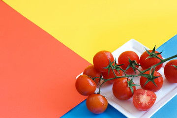 Cherry tomatoes on a blue, yellow and coral red background