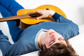 Young man with closed eyes practicing guitar