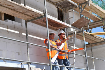 construction manager and architect on site during the construction of a house - planning and control on site - teamwork