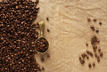 Coffee beans on burlap and spoon with coffee beans. Coffee background