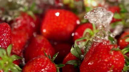 Strawberry watering. Close up of crop of picked freshly red berry and green leaves in cold water with chaotic motion.