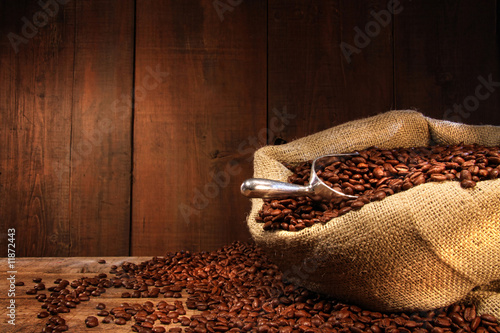  Burlap sack of coffee beans against dark wood
