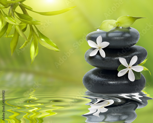 Fototapeta Spa still life, with white flowers on the black stones and bambo