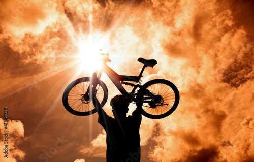 Fototapeta The Silhouette of mountain biker raised bicycle