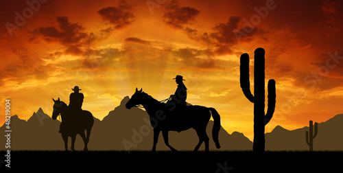 Silhouette cowboys with horses in the sunset
