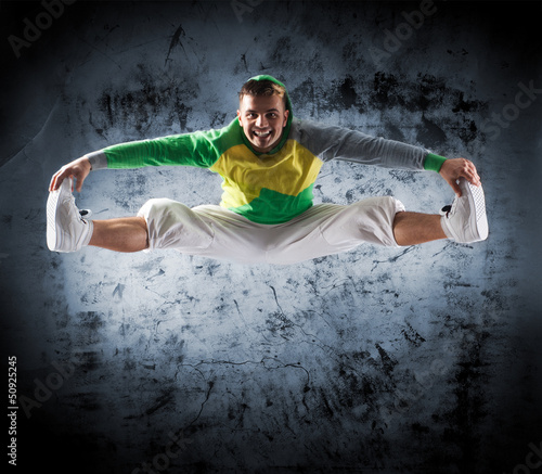 Fototapeta Young and sporty modern dancer over the dramatic background
