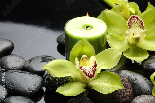zielona-orchidea-i-swieczka-na-czarnych-kamieniach