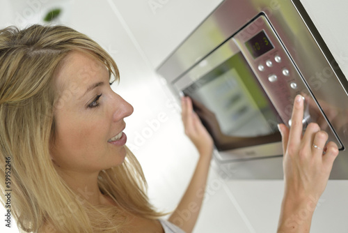 Woman at home using microwave oven