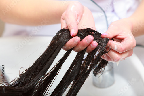 Fototapeta Hairstylist washing woman hair. Hairdressing beauty salon