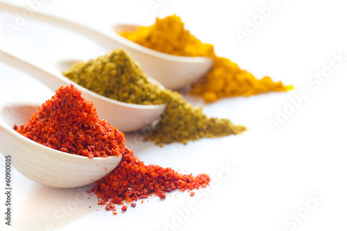 Spices in wooden spoons on a white background closeup