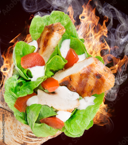 Fototapeta Chicken slices in a Tortilla with fire.