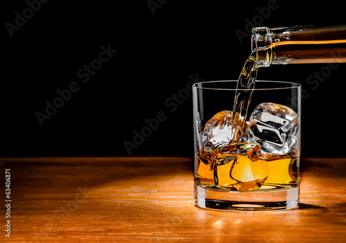 Fototapeta Pouring whiskey drink into glass
