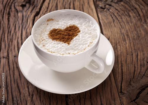 Fototapeta Cup of cappuccino with ground cinnamon in the form of heart.