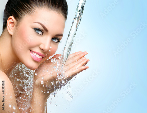 Fototapeta Beautiful smiling girl under splash of water