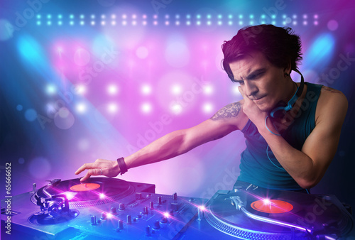  Disc jockey mixing music on turntables on stage with lights and