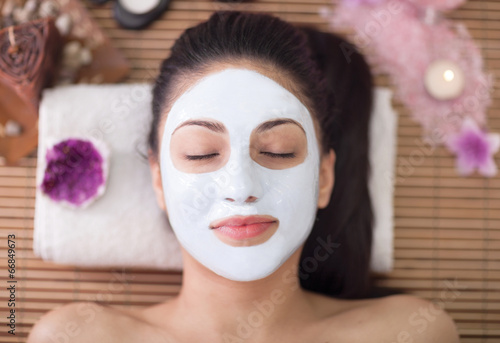Fototapeta Spa therapy for young woman having facial mask at beauty salon